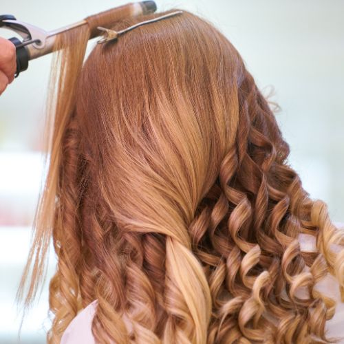 A woman is cutting her hair with a pair of scissors