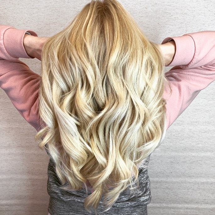 A woman with long blonde hair standing in front of a wall